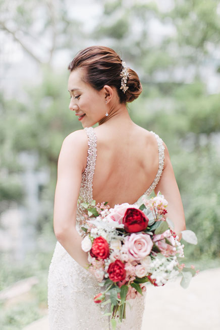 bride holds bouquet with backless gown